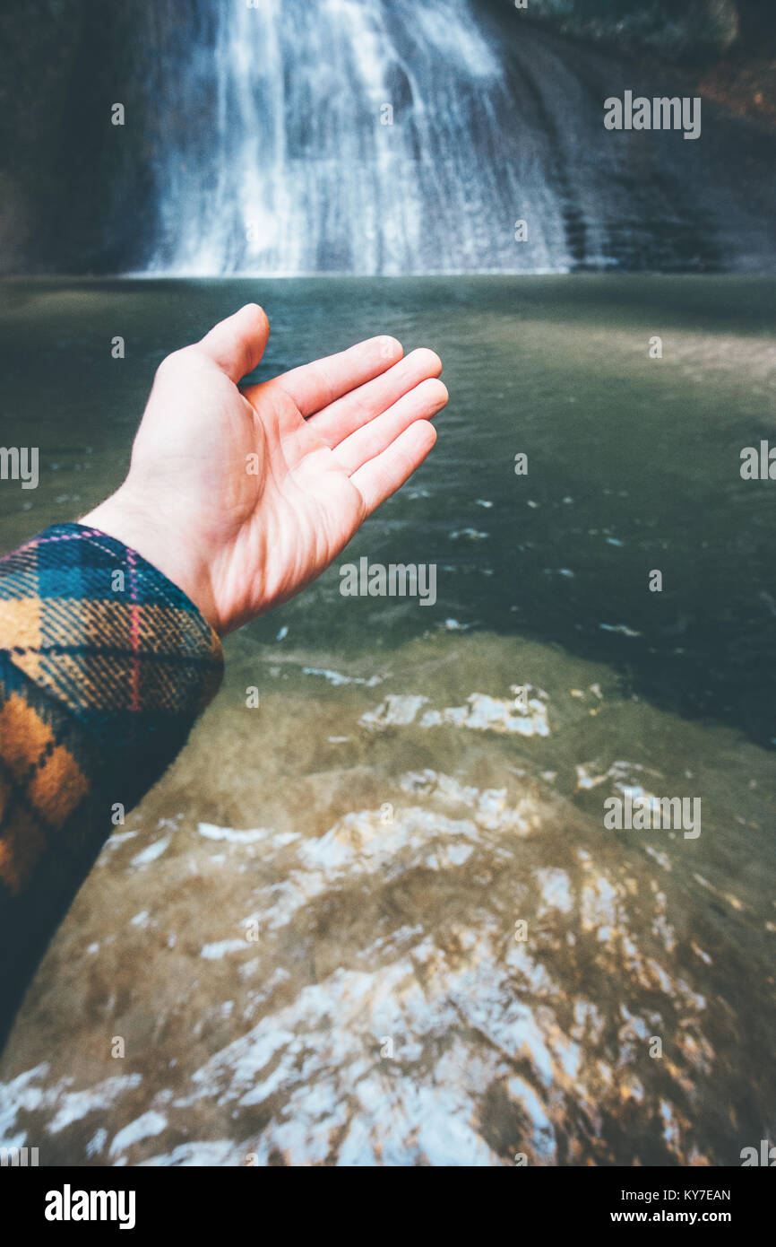 Man Hand showing Waterfall Landscape Travel Lifestyle adventure concept active vacations into the wild harmony with nature Stock Photo