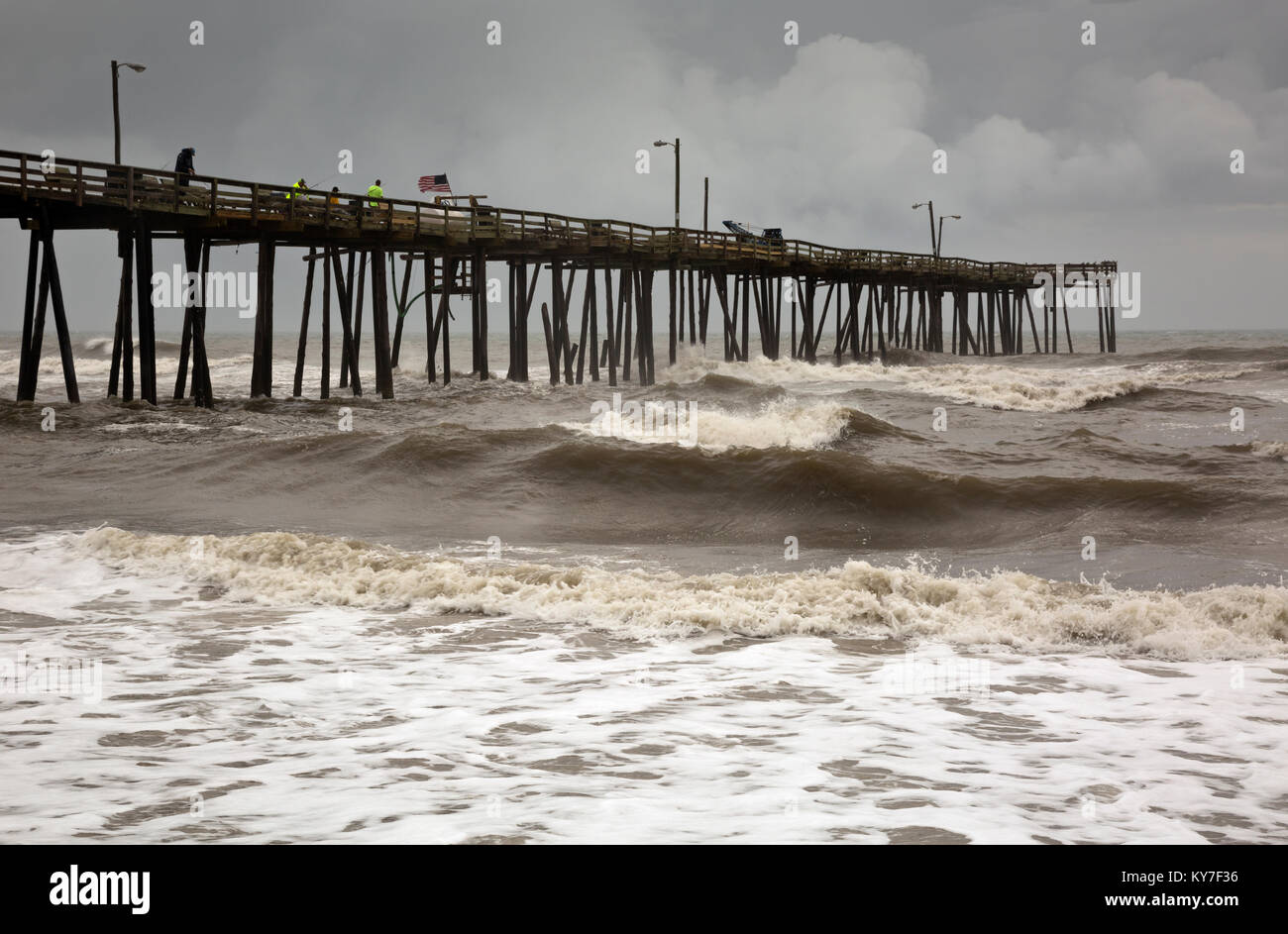 NC01271-00...NORTH CAROLIINA - Fishing on the Nags Head Pier in the face of a large storm coming in over the Atlantic Ocean. Stock Photo