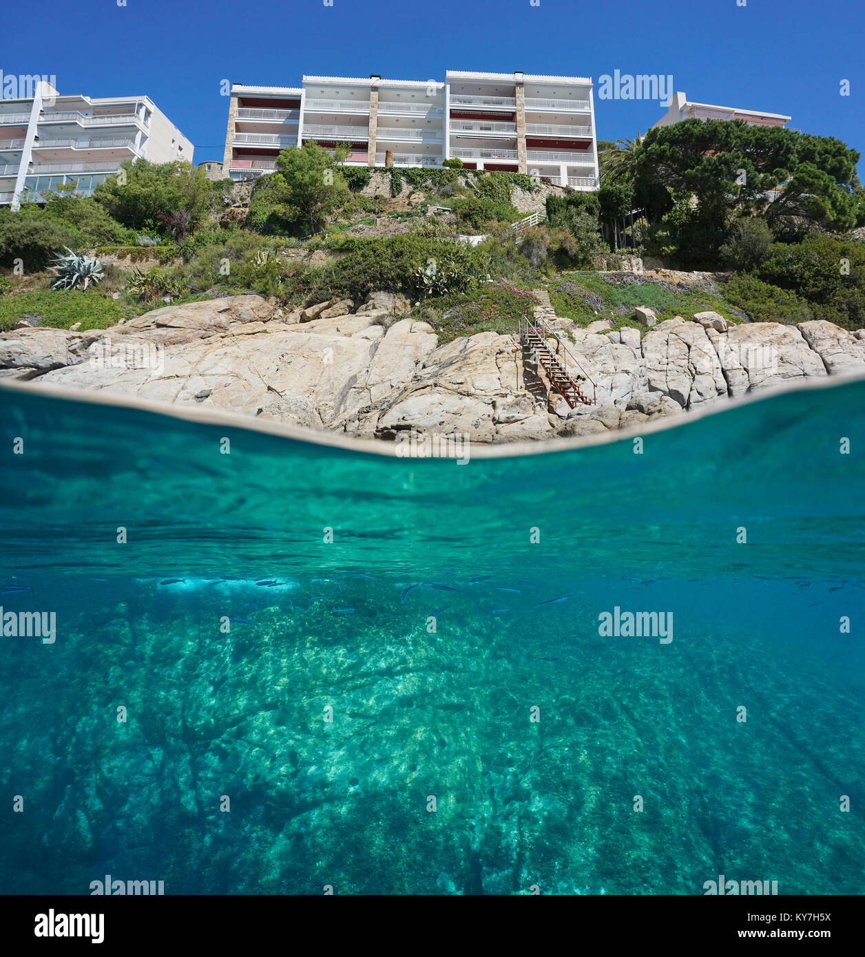 Over and under sea surface, apartment buildings with stair leading to rocky shore and rock underwatern, Spain, Costa Brava, Mediterranean, Girona Stock Photo