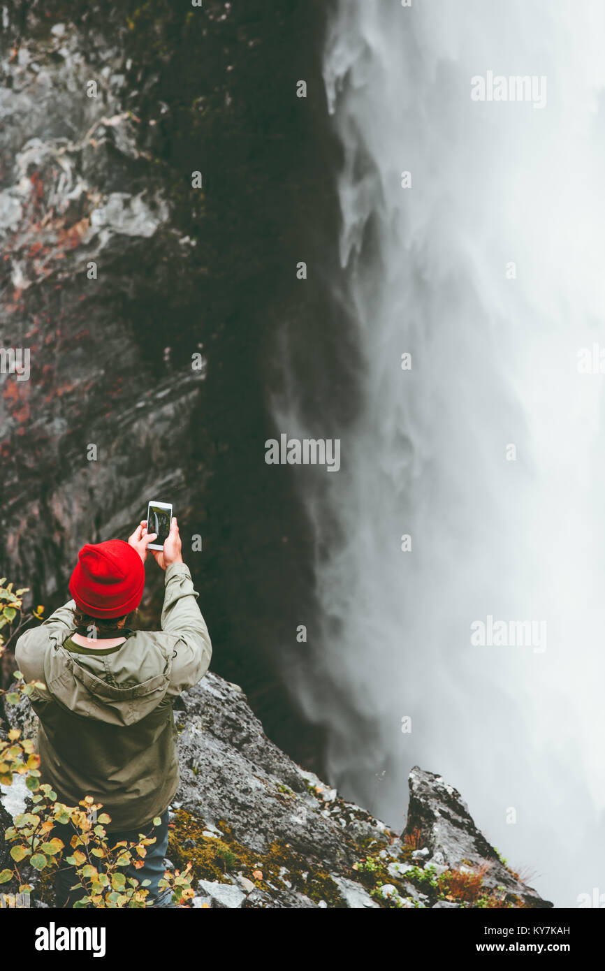 Man taking photo of Vettisfossen waterfall by smartphone adventure lifestyle concept vacations outdoor wanderlust Stock Photo