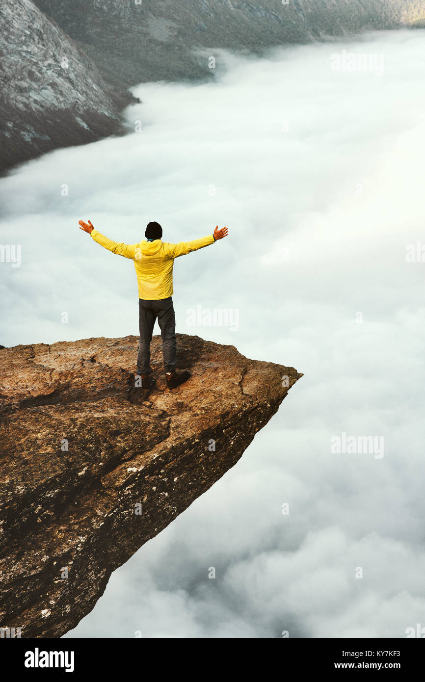 Man tourist success raised hands on Trolltunga rocky cliff edge in Norway mountains Travel Lifestyle adventure concept vacations outdoor above clouds Stock Photo
