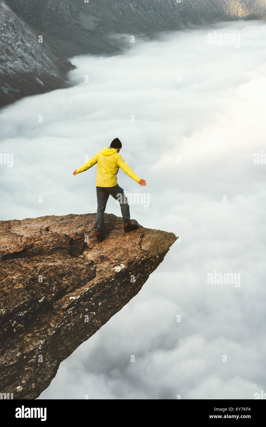 Man tourist on Trolltunga rocky cliff edge mountains Travel Lifestyle adventure emotional concept wanderlust vacations in Norway outdoor above clouds Stock Photo