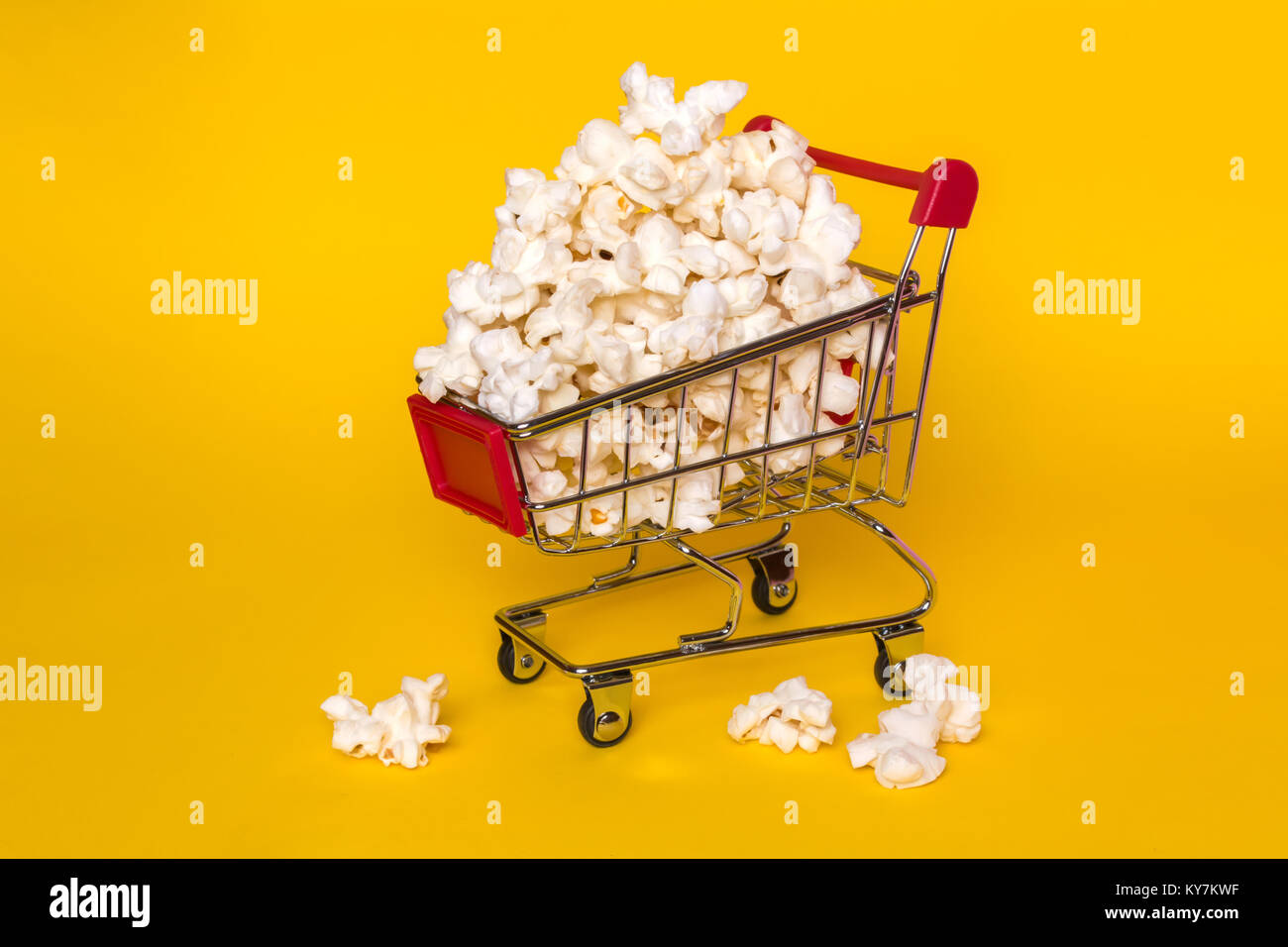 Popcorn in a shopping trolley. A bunch of popcorn on a white background. Surrealistic concept Stock Photo
