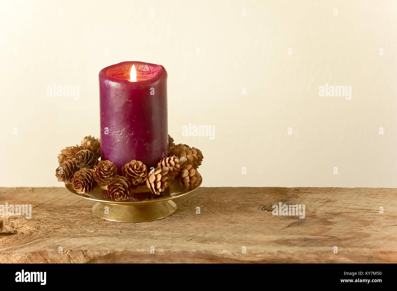 Purple Holiday Candle Simple Decoration with Pinecones on Rustic Wood
