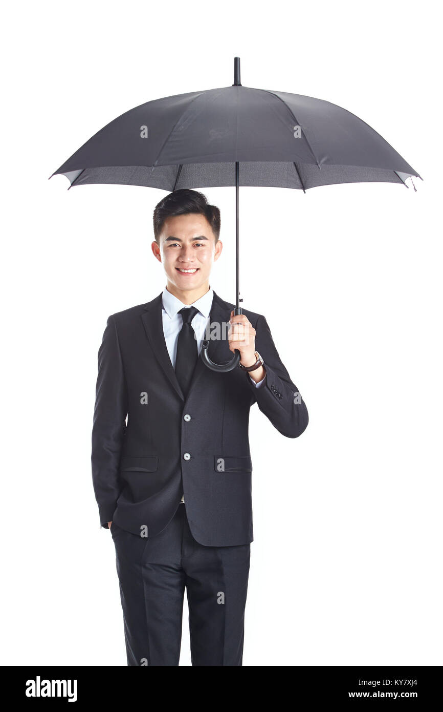 studio shot of a young asian business man holding a black umbrella, happy and smiling, isolated on white background. Stock Photo