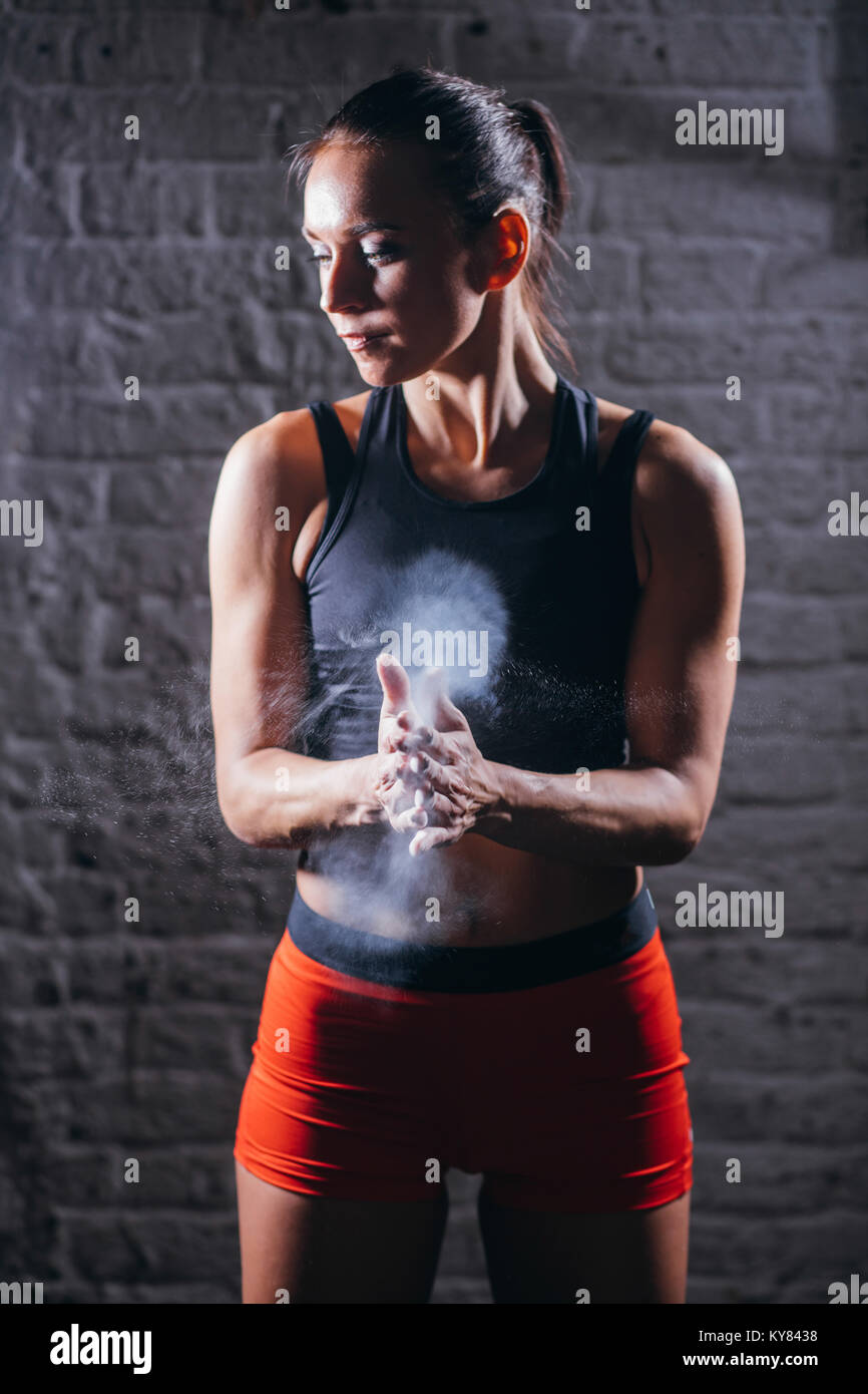 female athlete clapping hands with chalk powder before strength
