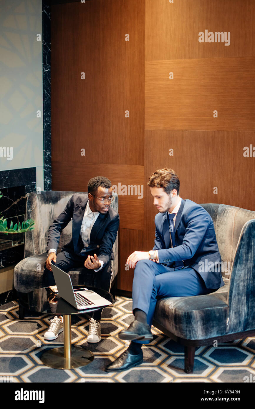 Discuss Info businessman using laptop to discuss information with colleague in ...