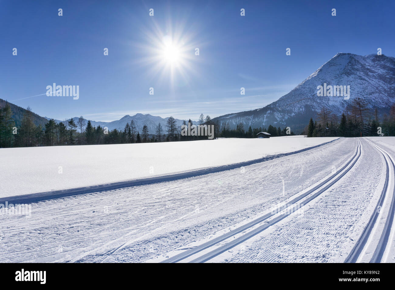 Winter mountain landscape with groomed ski track and blue sky in sunny day. Tirol, Alps, Austria. Stock Photo