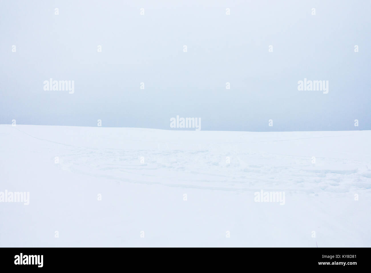 Soft Minimaliste Landscape of Snow Field with Snowmobile Tracks and Cloudy Sky Stock Photo