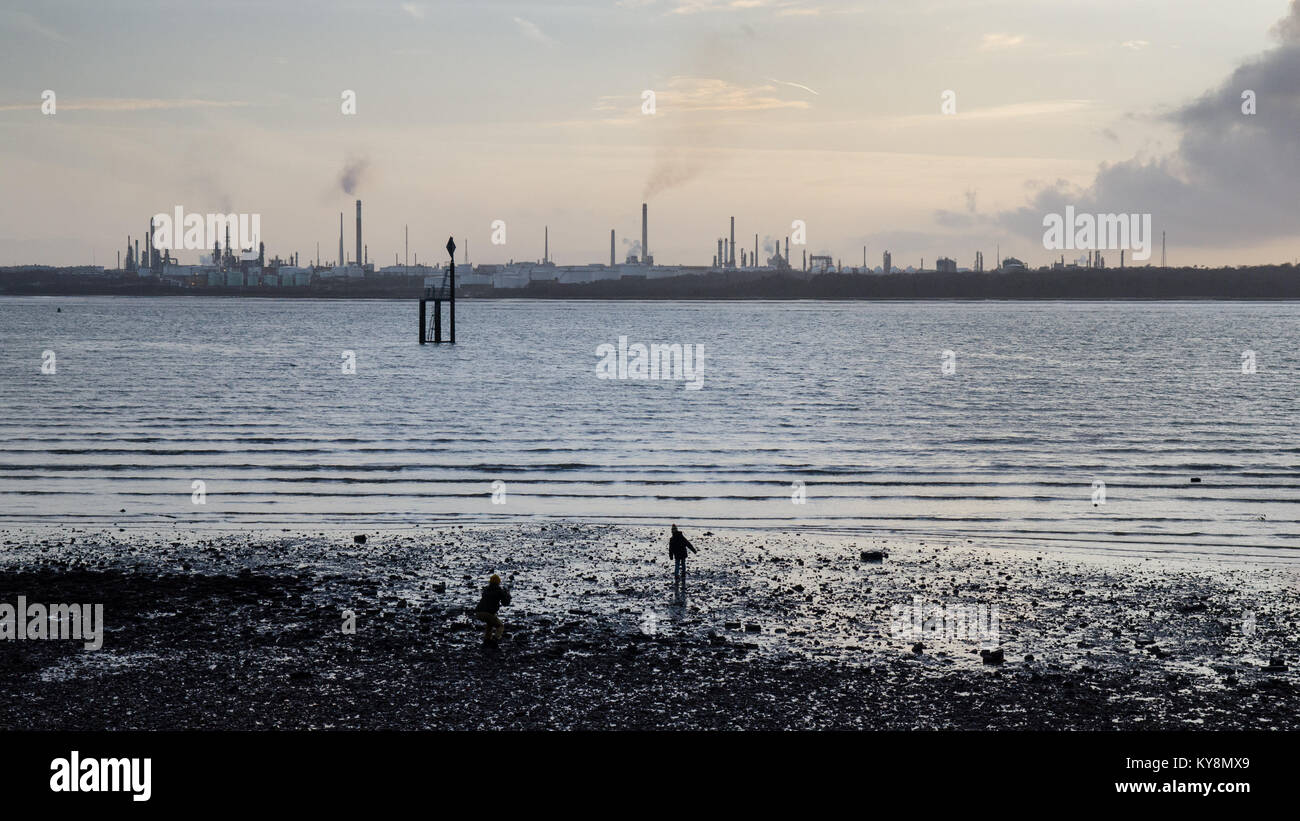 The sunset silhouettes the industrial towers of Fawley oil refinery on the shores of Southampton Water, seen from Netley. Stock Photo