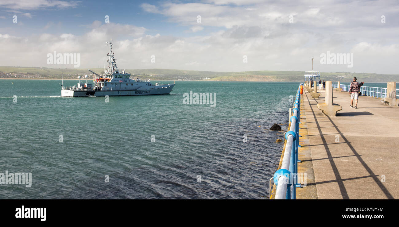 UK Border Agency customs cutter HMC Valiant passes the Stone Pier leaving Weymouth Harbour in Dorset. Stock Photo
