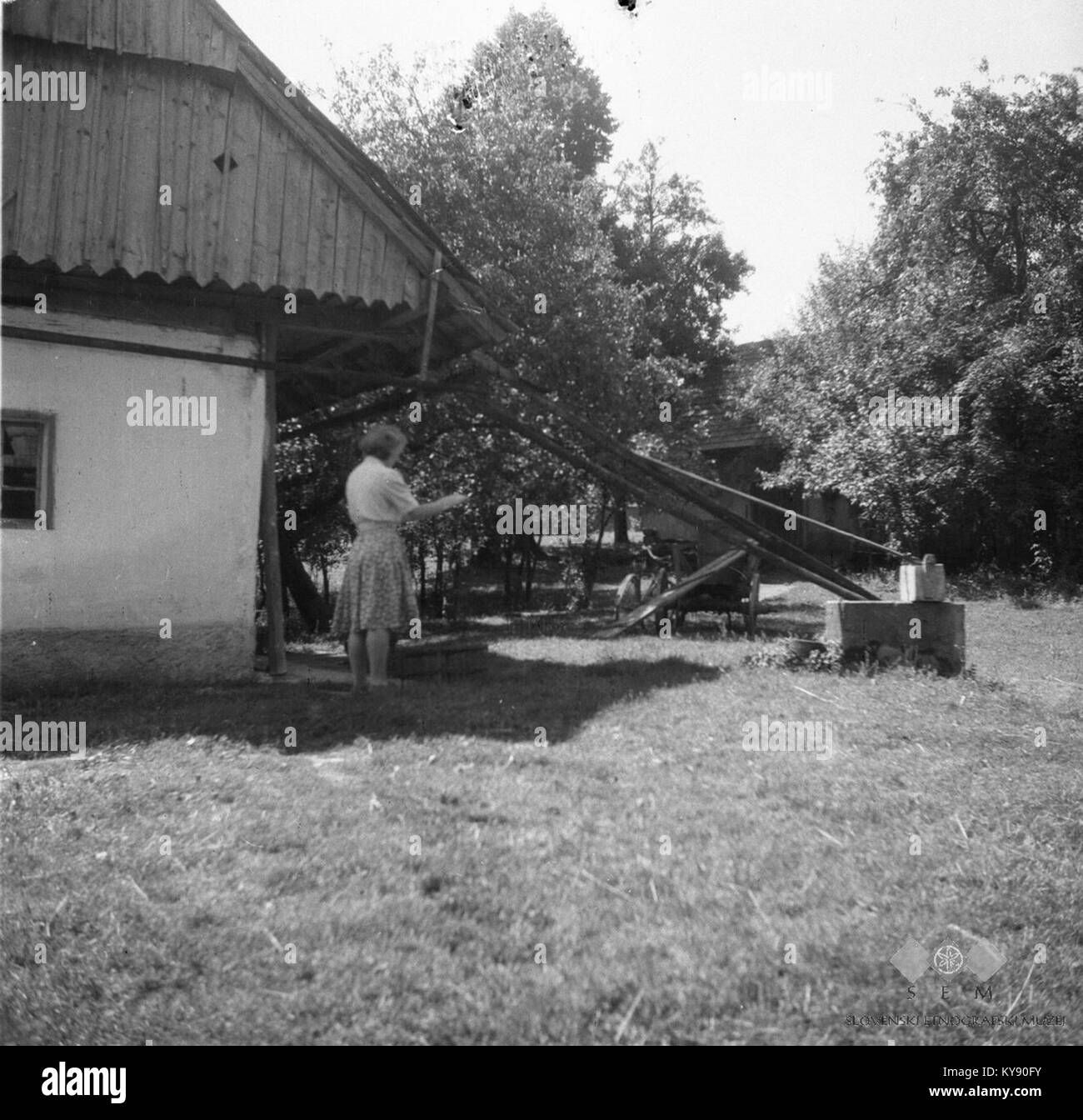 Tov. Šuštar riše vodnjak- šterno- z lesenim vedrom, Sela, pri Anzeljnu 1949 Stock Photo