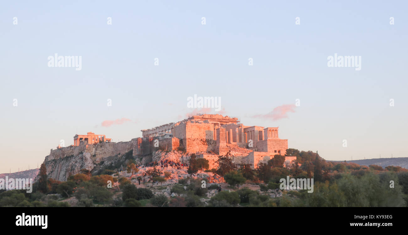 View of the Acropolis in Athens Greece at sunset with the pink light reflecting off it and pink clouds in the sky - people are watching the sunset fro Stock Photo