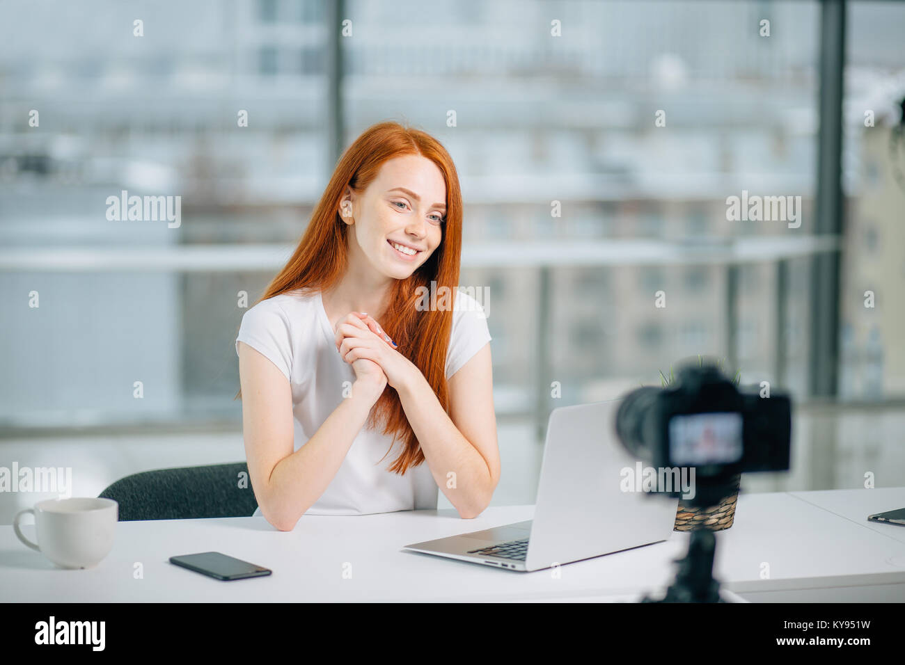 Young woman recording video on camera mounted on tripod for her vlog Stock Photo