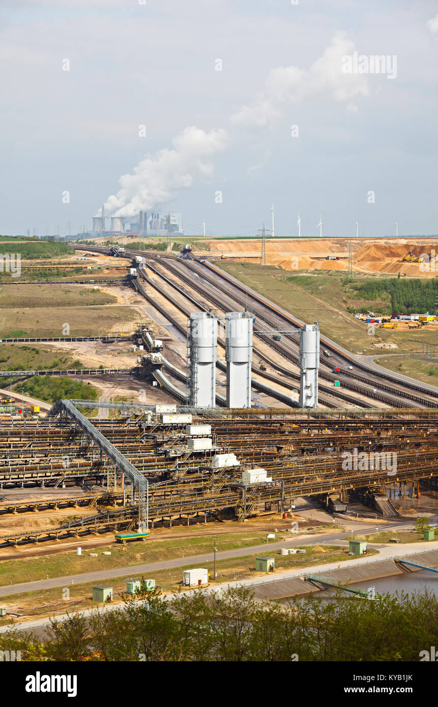 A brown coal pit mine with conveyor belts leading to a distant coal power station. Stock Photo