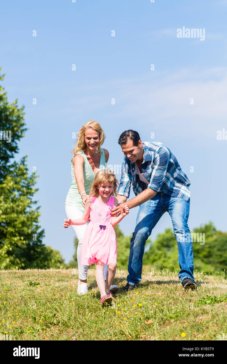 Father, mother, daughter running down a hill Stock Photo