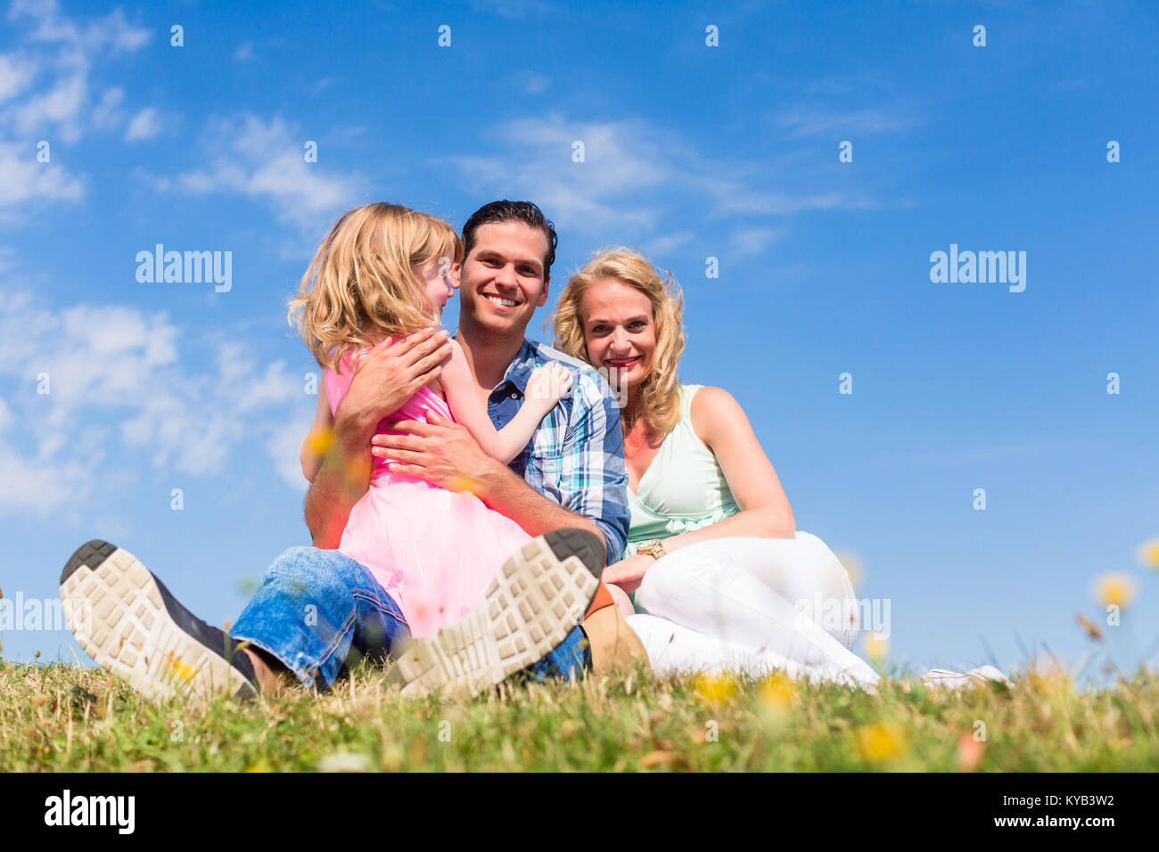 Family sitting in green grass on meadow Stock Photo