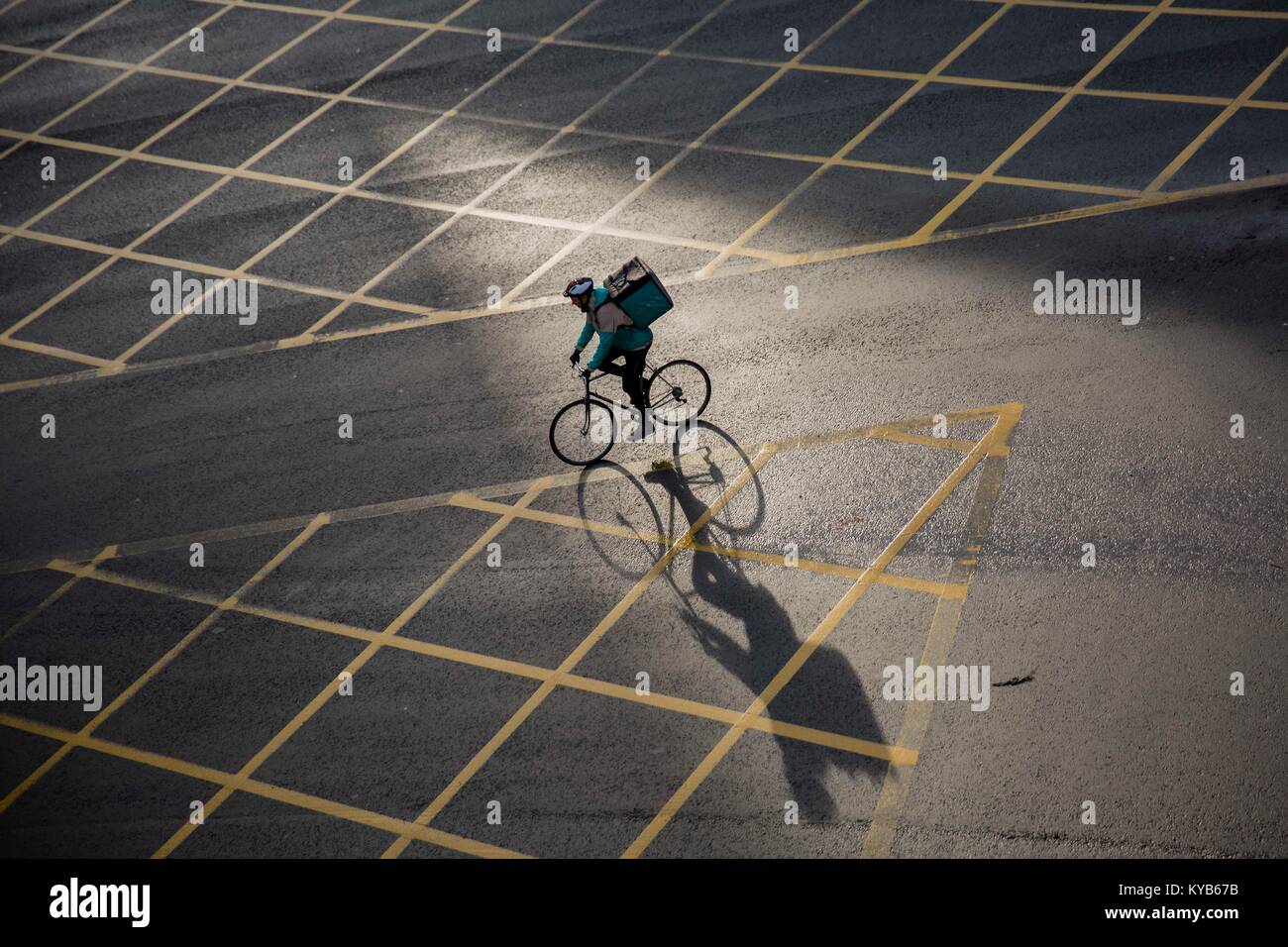 A Deliveroo cyclist courier and long winter shadows in Cardiff City Centre. Stock Photo