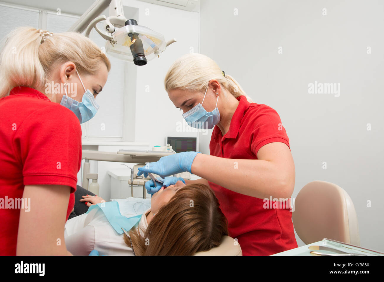 Medical dentist team in dental office with female patient preparing for