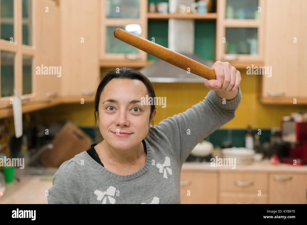 young and pretty angry housewife with a rolling pin in her hand Stock Photo