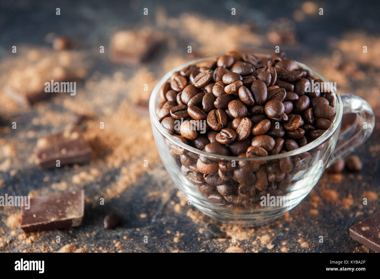 Full glass cup of Roasted coffee beans on the dark stone background with cocoa powder, pieces of chocolate and beans. Selective focus. Coffee love con Stock Photo