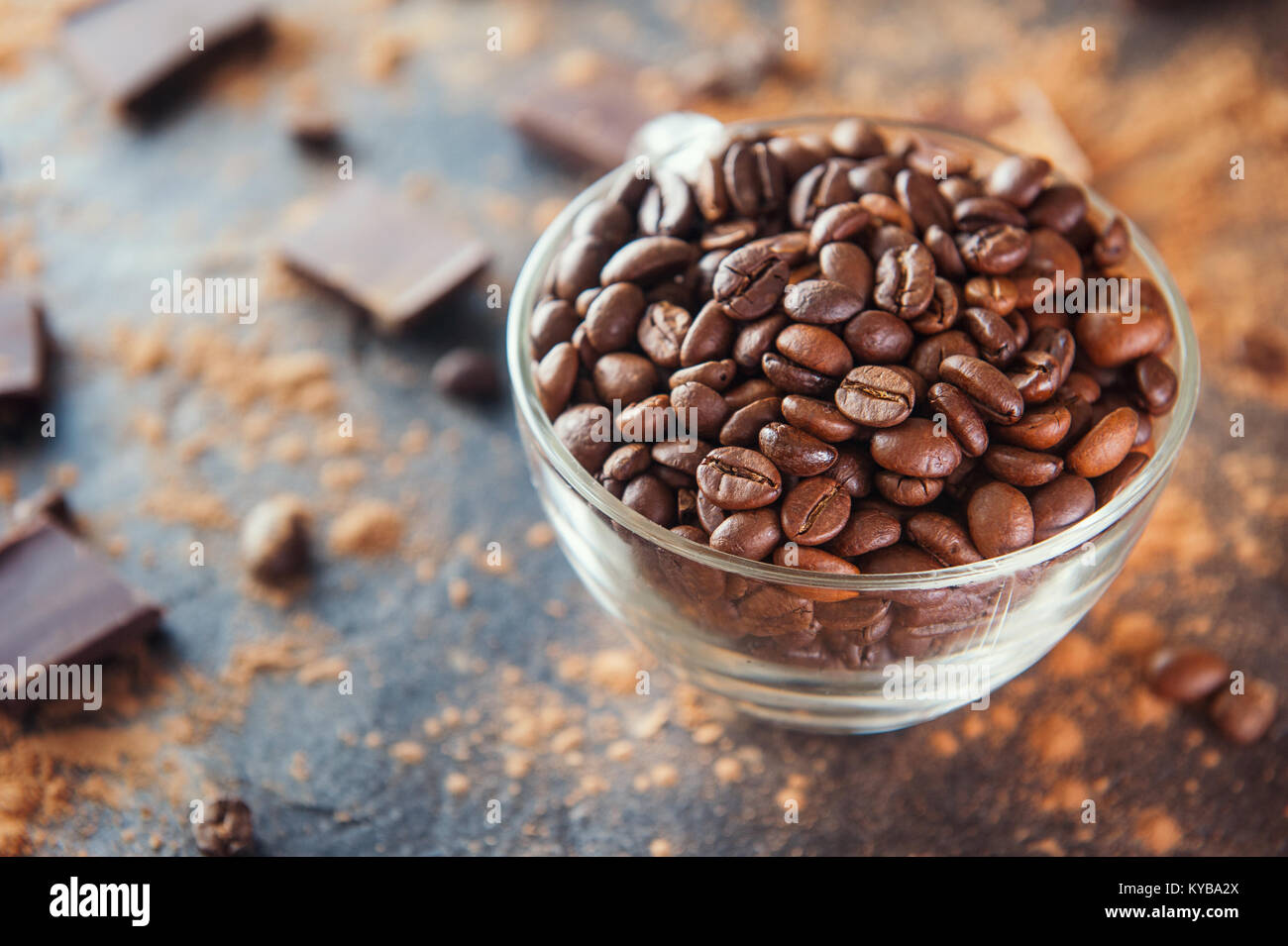 Full glass cup of Roasted coffee beans on the dark stone background with cocoa powder, pieces of chocolate and beans. Selective focus. Coffee love con Stock Photo