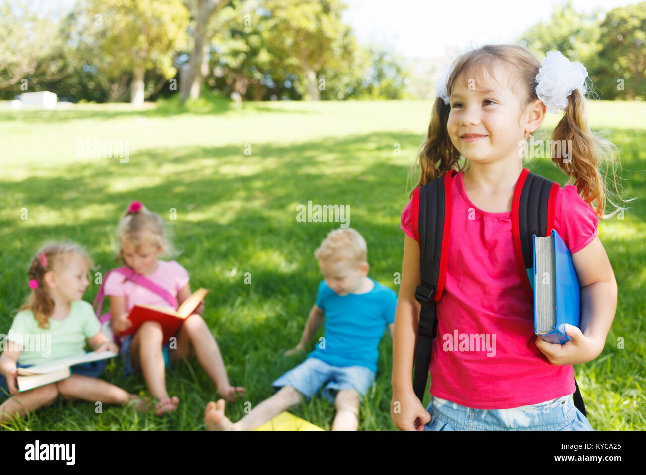 Preschooler girl with book and her friends Stock Photo