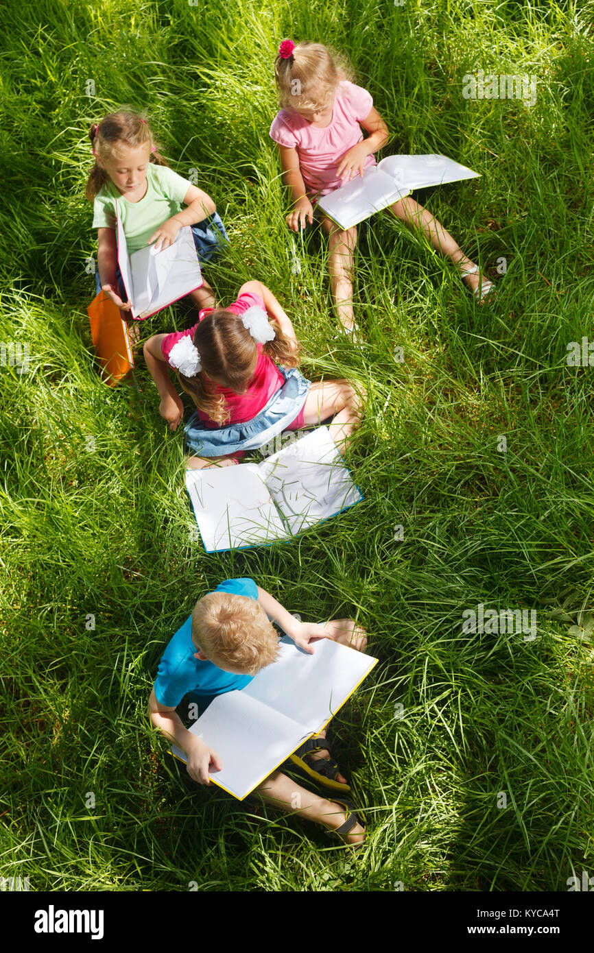 Preschoolers with books sitting on the grass Stock Photo