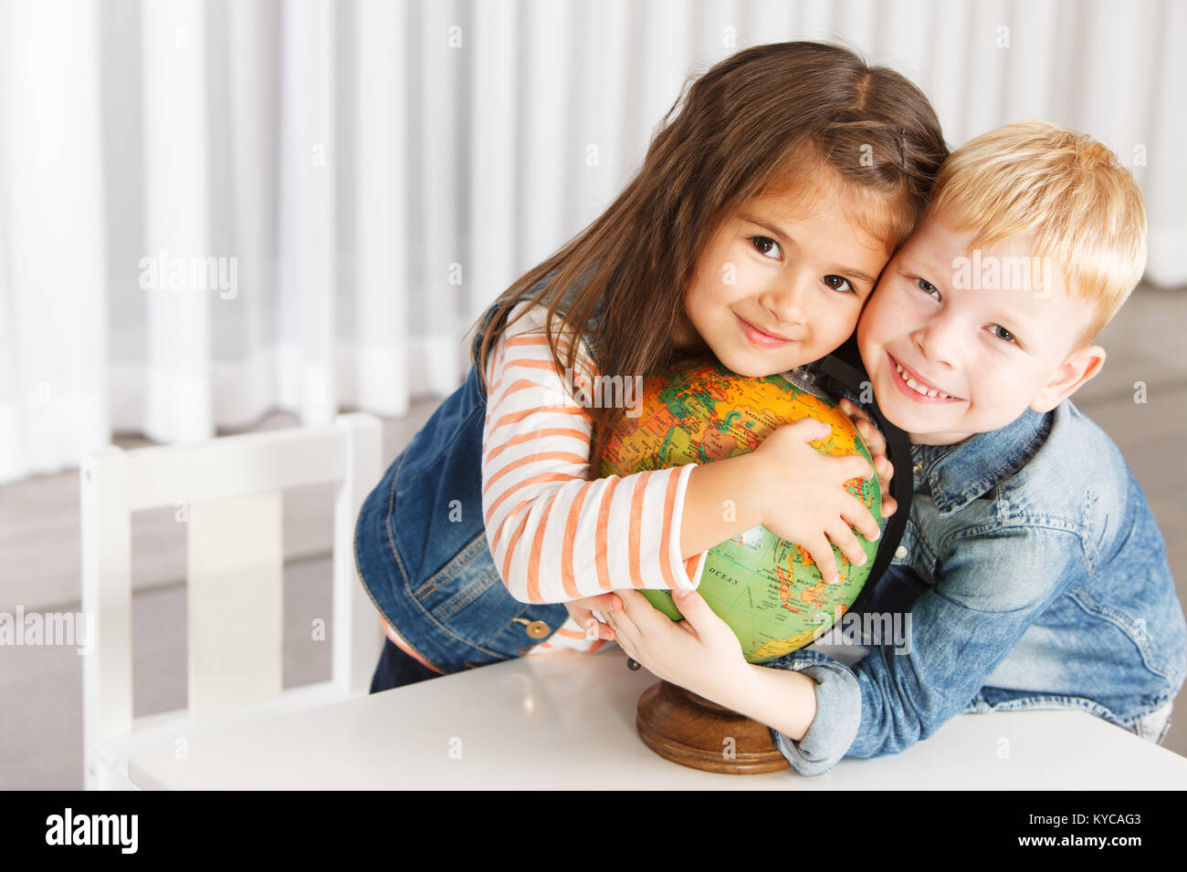Beautiful 5 years-old little children embracing the globe Stock Photo