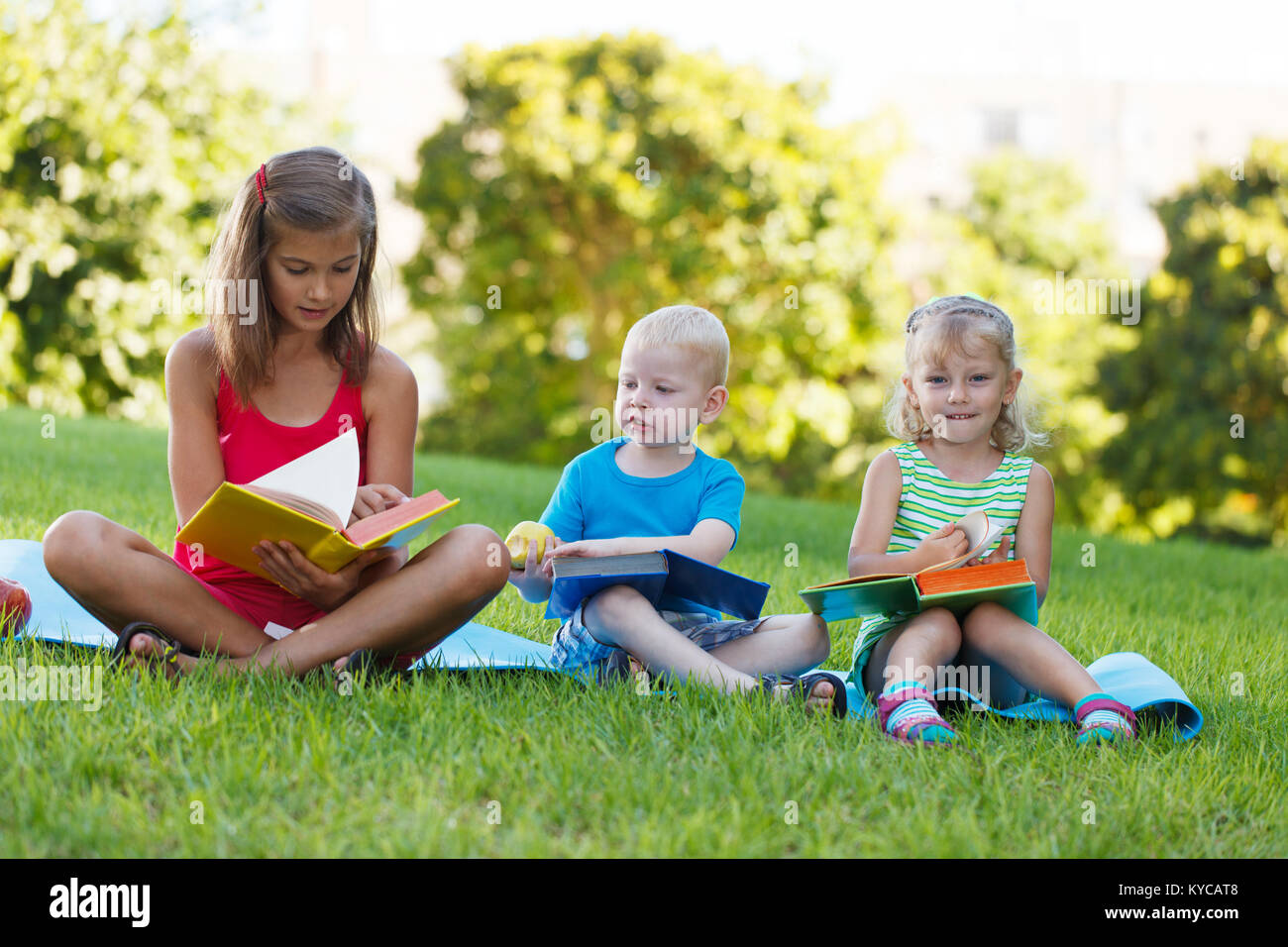 Three reading kids on the grass Stock Photo