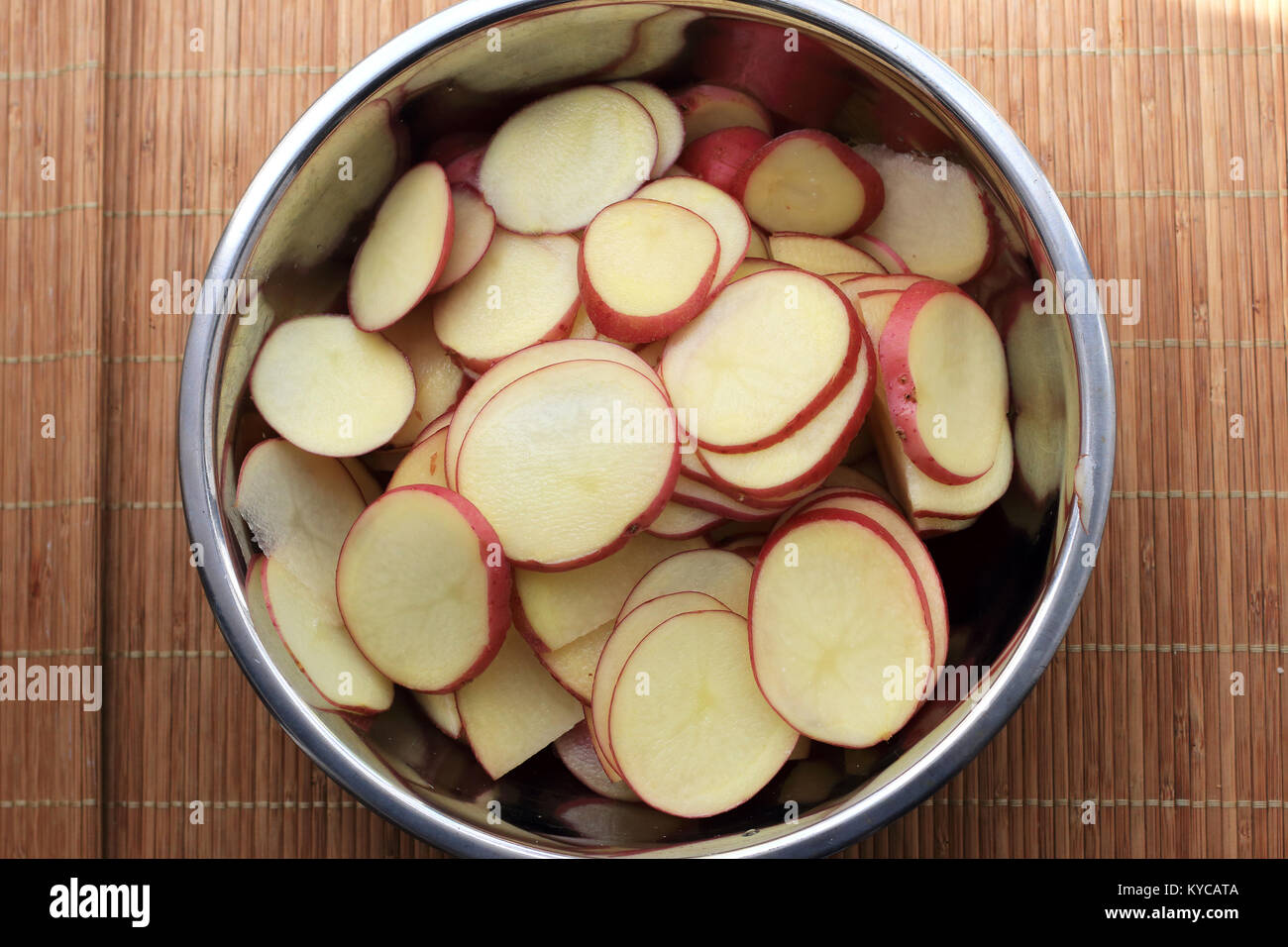 Thin Sliced Desiree Potatoes in mixing bowl Stock Photo