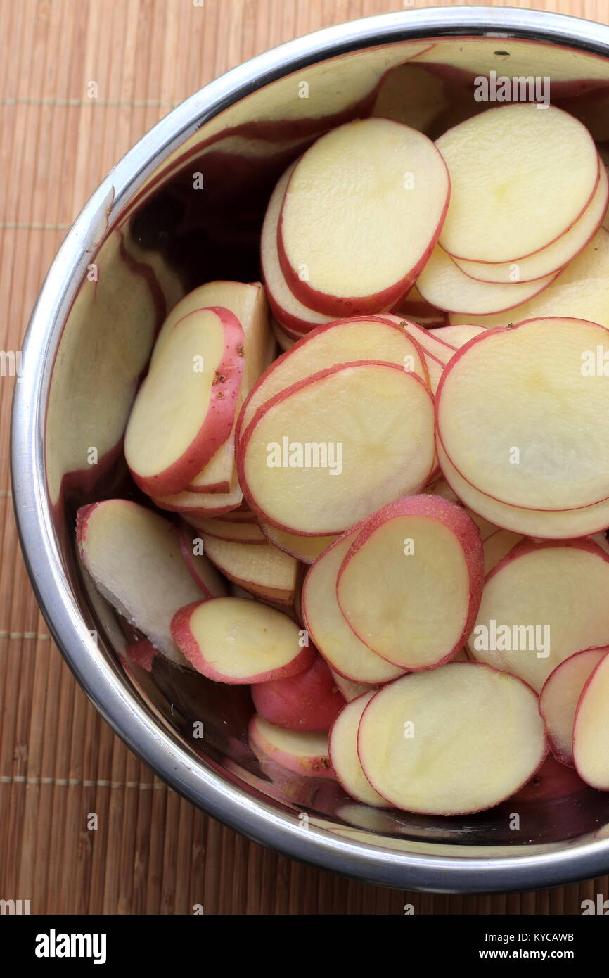 Thin Sliced Desiree Potatoes in mixing bowl Stock Photo