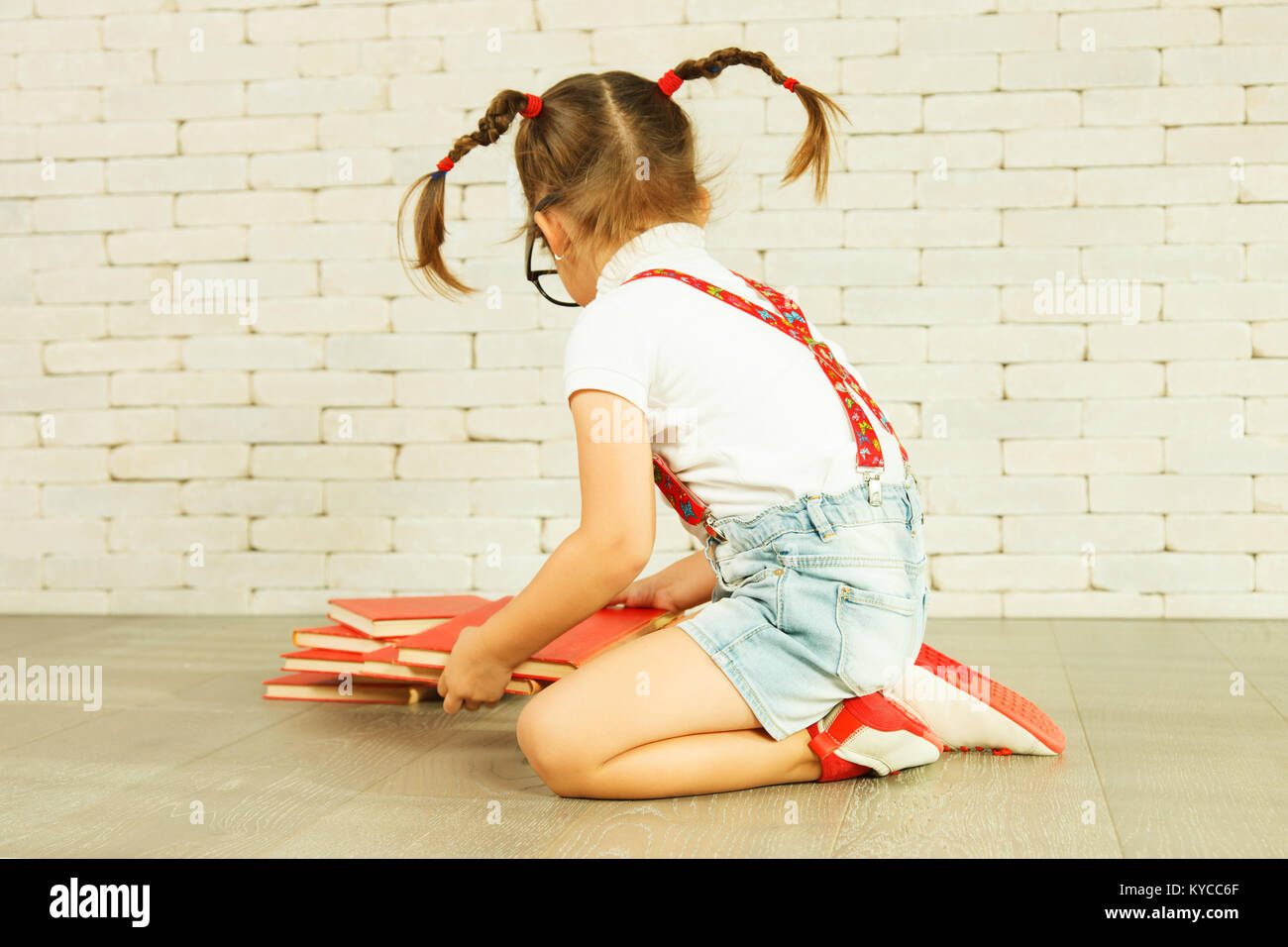 Preschooler girl with pigtails sitting on the floor Stock Photo