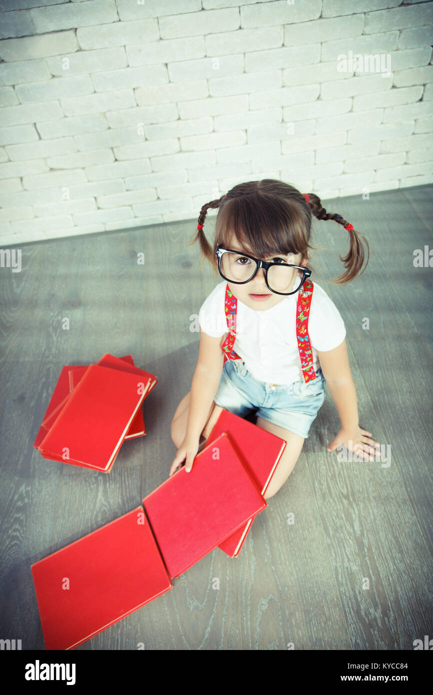 Little nerd girl looking at camera with big eyes wearing glasses. Stock Photo