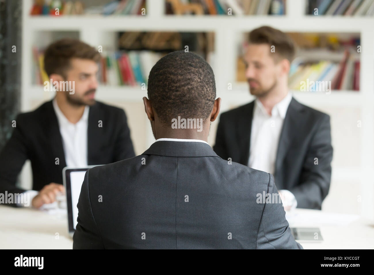 Rear view at african businessman against two caucasian men wearing ...