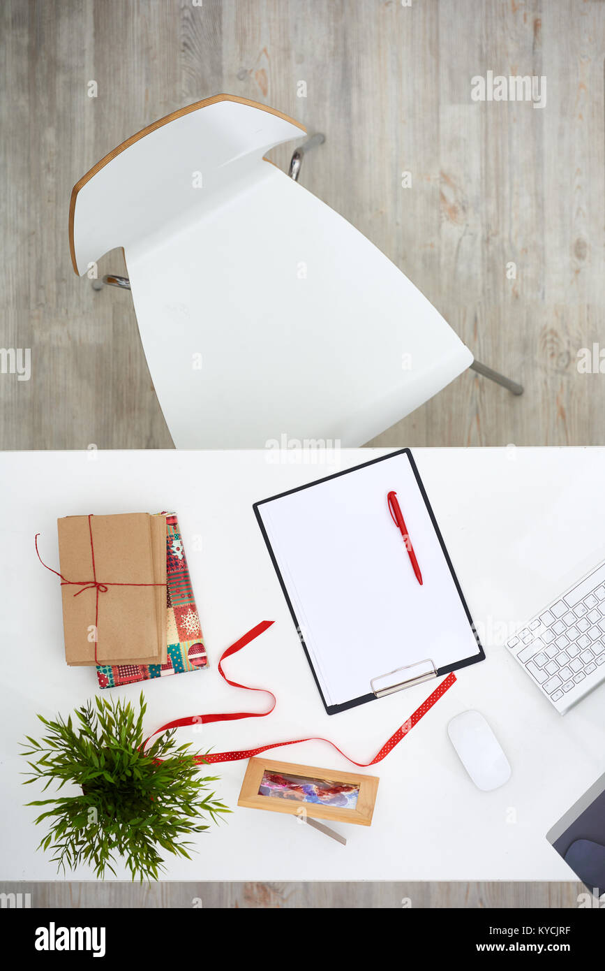 Modern office workplace: desktop with unwrapped Christmas present, computer and clipboard, directly above view Stock Photo