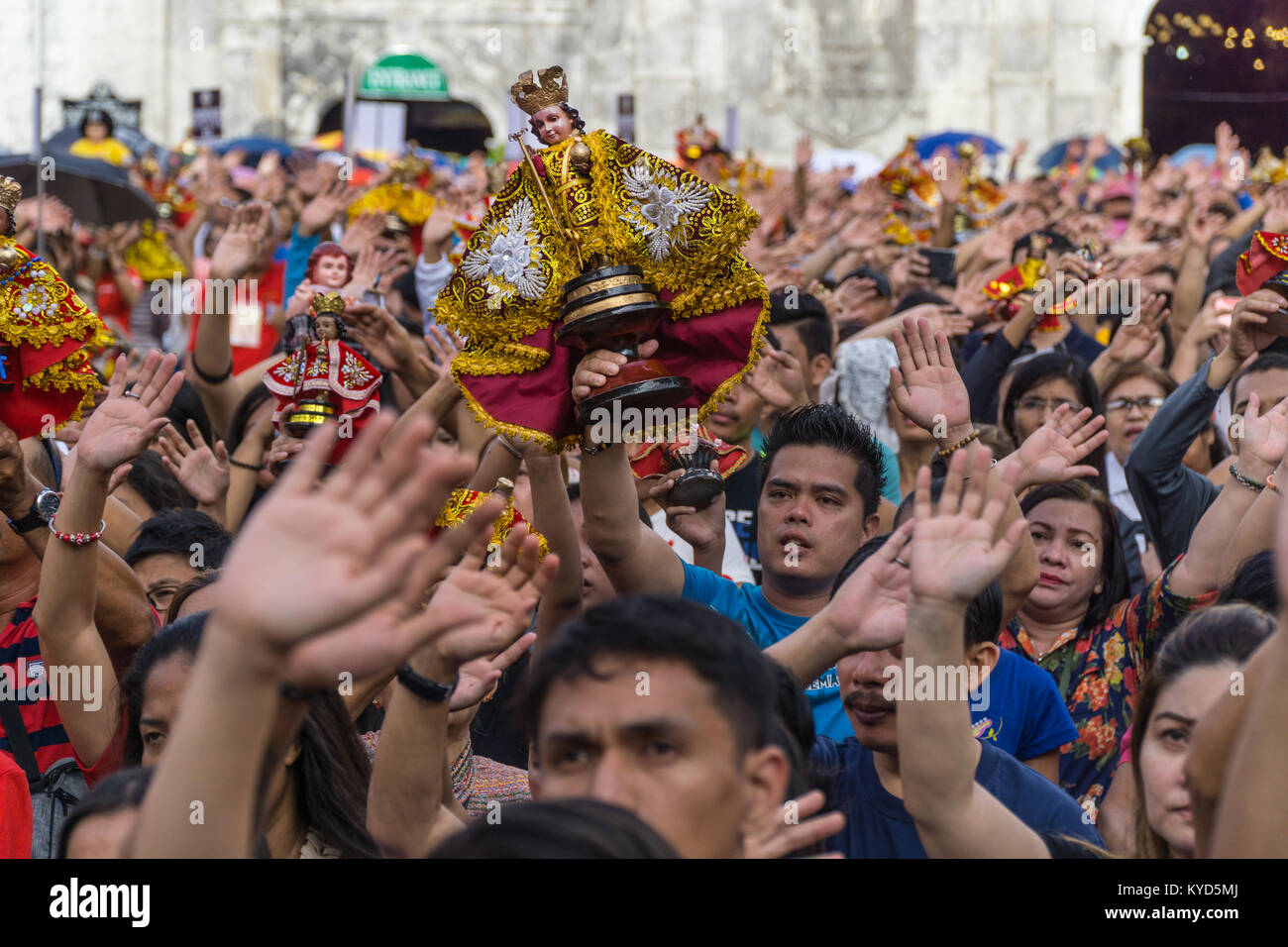 Cebu City, Philippines. 14th January, 2018.Filipino catholics raise hands in the air as they take part in singing of the hymn Batobalani sa Gugma.As part of the Sinulog 9 day religious festival,Filipino Catholics gather for early morning Sunday mass bringing with them Santo Nino figurines,replicas of the child Jesus.The belief in this Effigy dates back to the time of explorer Ferdinand Magellan who gave the original figurine as a gift when he landed in 1521 at Cebu. Credit: imagegallery2/Alamy Live News Stock Photo
