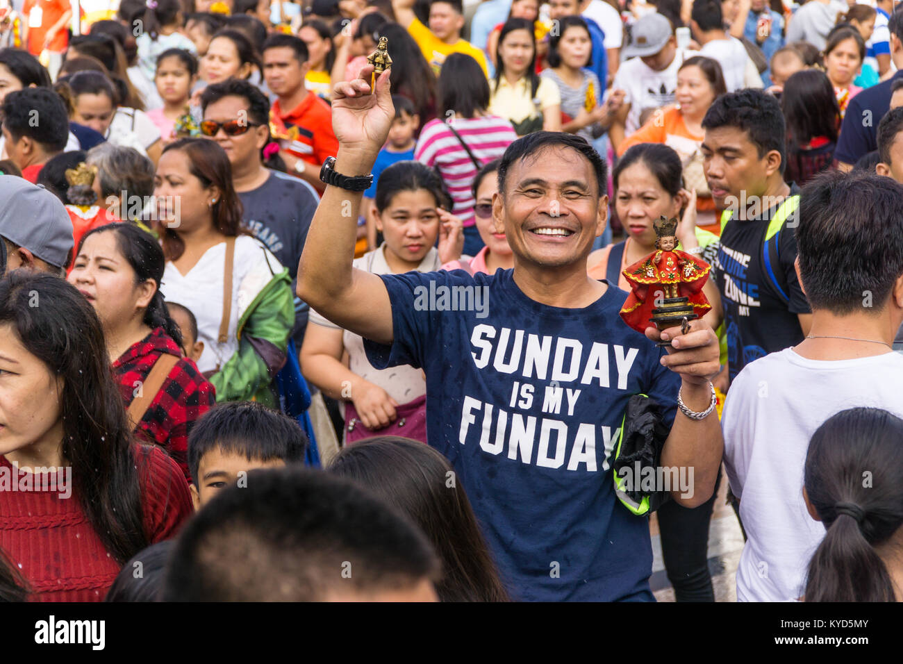 Cebu City, Philippines. 14th January, 2018. A happy & smiling man holds up two Santo Nino figurines.As part of the Sinulog 9 day religious festival,Filipino Catholics gather for early morning Sunday mass bringing with them Santo Nino figurines,replicas of the child Jesus.The belief in this Effigy dates back to the time of explorer Ferdinand Magellan who gave the original figurine as a gift when he landed in 1521 at Cebu. Credit: imagegallery2/Alamy Live News Stock Photo