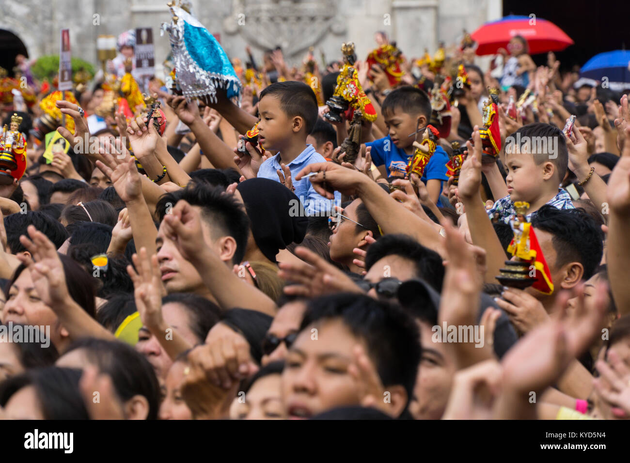 Cebu City, Philippines. 14th January, 2018. Children lofted above the heads of their parents as hands are waved in the air during singing of the hymn Bato balani Sa Gugma.As part of the Sinulog 9 day religious festival,Filipino Catholics gather for early morning Sunday mass bringing with them Santo Nino figurines,replicas of the child Jesus.The belief in this Effigy dates back to the time of explorer Ferdinand Magellan who gave the original figurine as a gift when he landed in 1521 at Cebu. Credit: imagegallery2/Alamy Live News Stock Photo