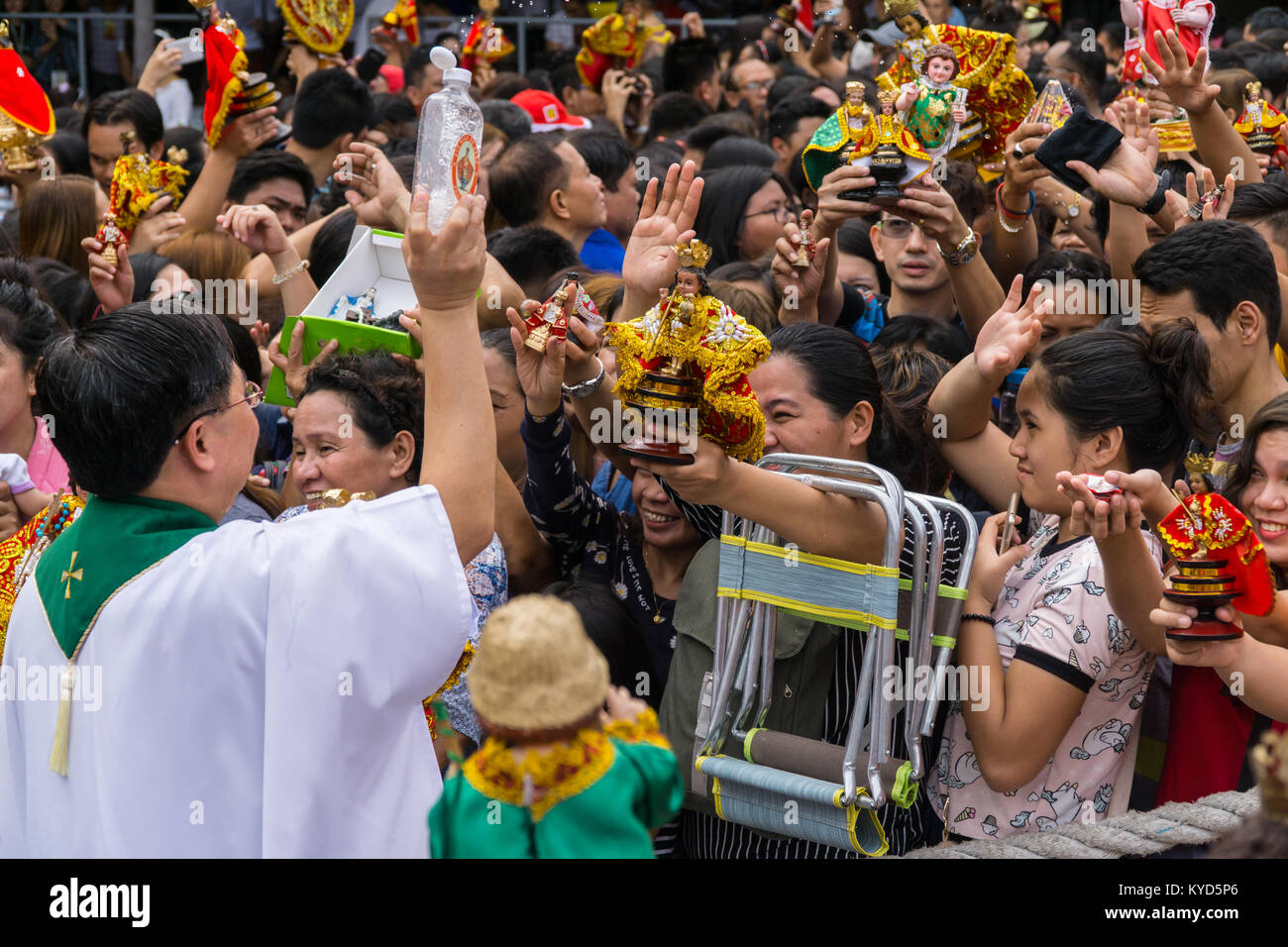 Cebu City, Philippines. 14th January, 2018. In the form of a blessing a priest showers the anticipating crowd with Holy Water.As part of the Sinulog 9 day religious festival,Filipino Catholics gather for early morning Sunday mass bringing with them Santo Nino figurines,replicas of the child Jesus.The belief in this Effigy dates back to the time of explorer Ferdinand Magellan who gave the original figurine as a gift when he landed in 1521 at Cebu. Credit: imagegallery2/Alamy Live News Stock Photo