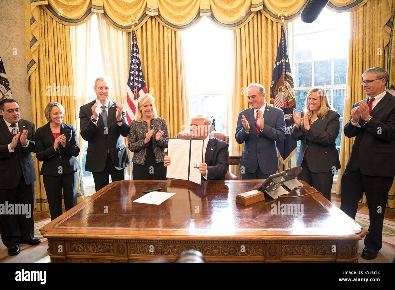 U.S. President Donald Trump holds up the signed executive order to Support our Veterans during their Transition from Uniformed Service to Civilian Life, during a ceremony in the Oval Office of the White House January 9, 2018 in Washington, DC.  Standing with the president is Homeland Security Secretary Kirstjen Nielsen, left, and Veterans Affairs Secretary David Shulkin, right. Stock Photo