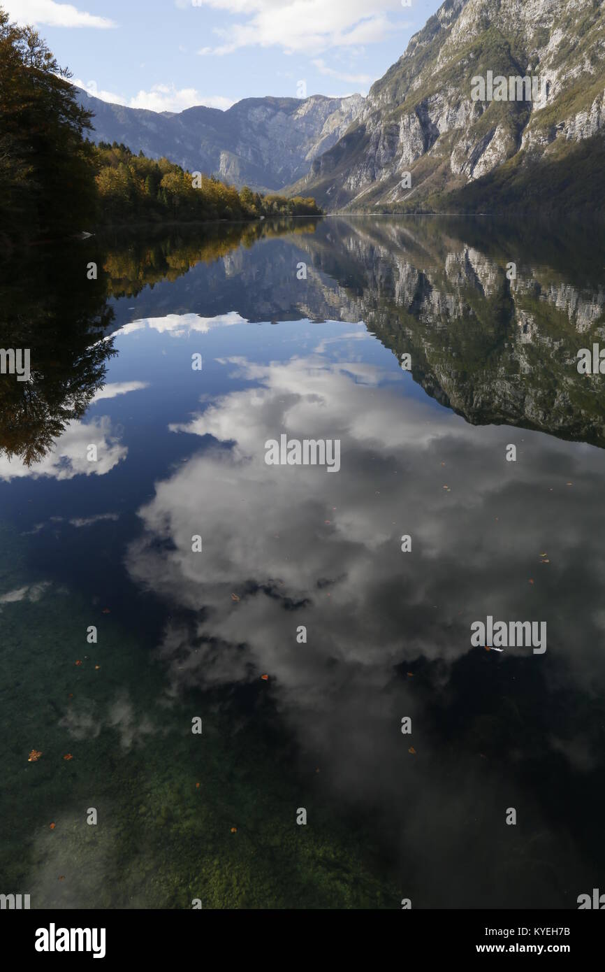 Mirror-like reflections of clouds and mountains in a calm Lake Bohinj, Slovenia. Autumn 2016 Stock Photo