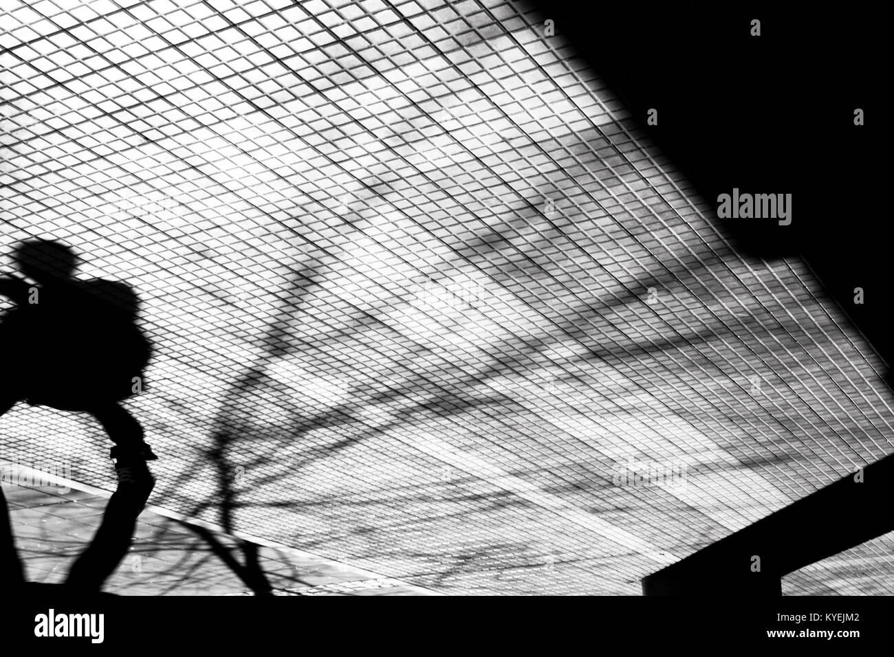 Blurry silhouette shadow of a person walking on a city sidewalk in winter in black and white high contrast Stock Photo