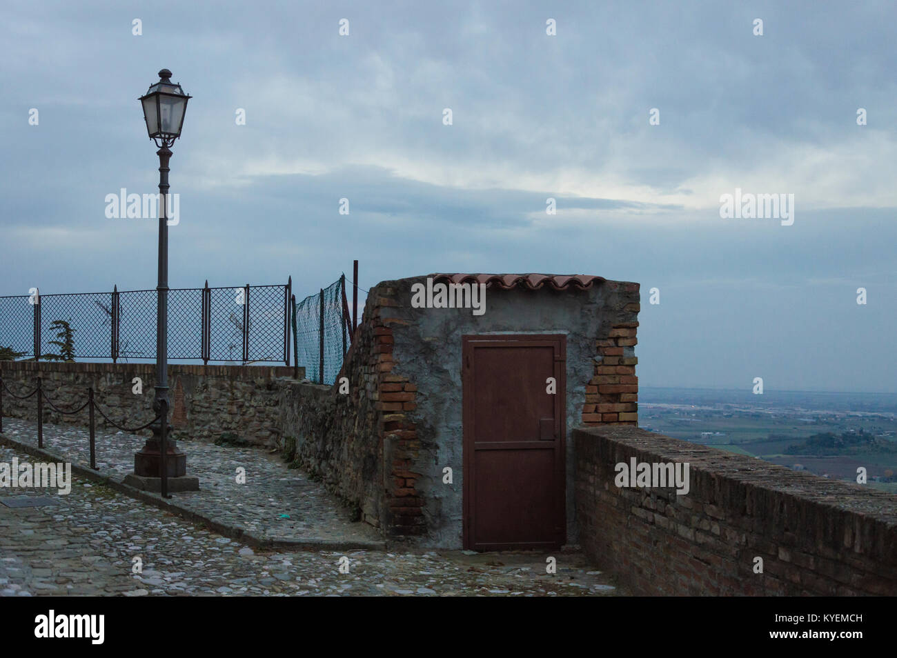 External wooden door in an old guard post of a surrounding wall with street lights Stock Photo