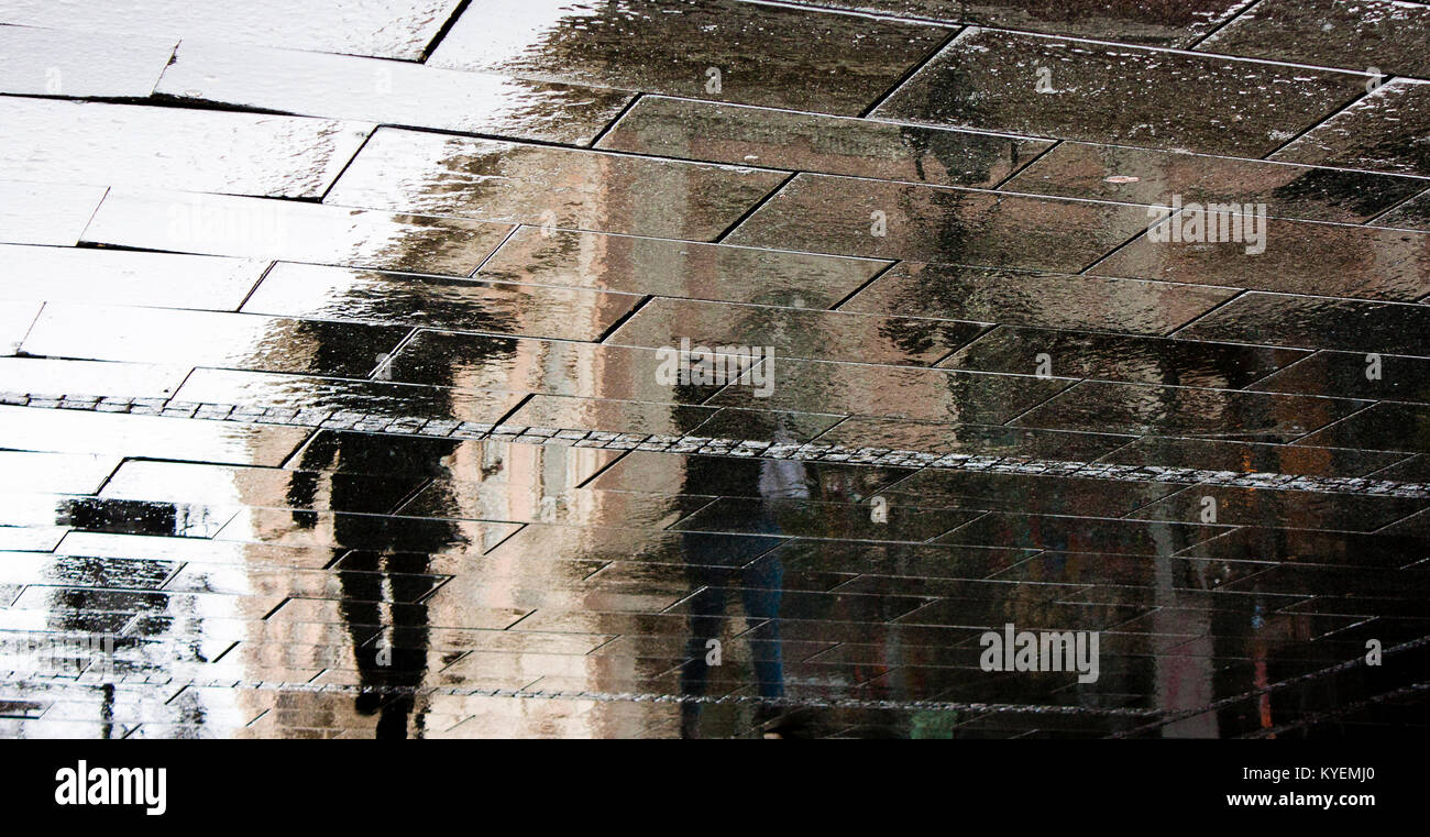 Rain reflection silhouette shadow of people on wet city streets on a rainy day Stock Photo
