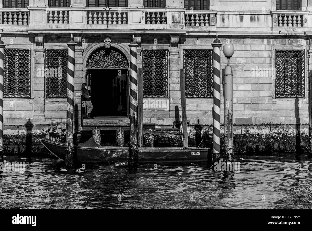 VENICE-MARCH 9:a boat in front the main entrance of an old building while an unidentified woman talks at the phone,Venice,Italy,on March 9,2017. Stock Photo