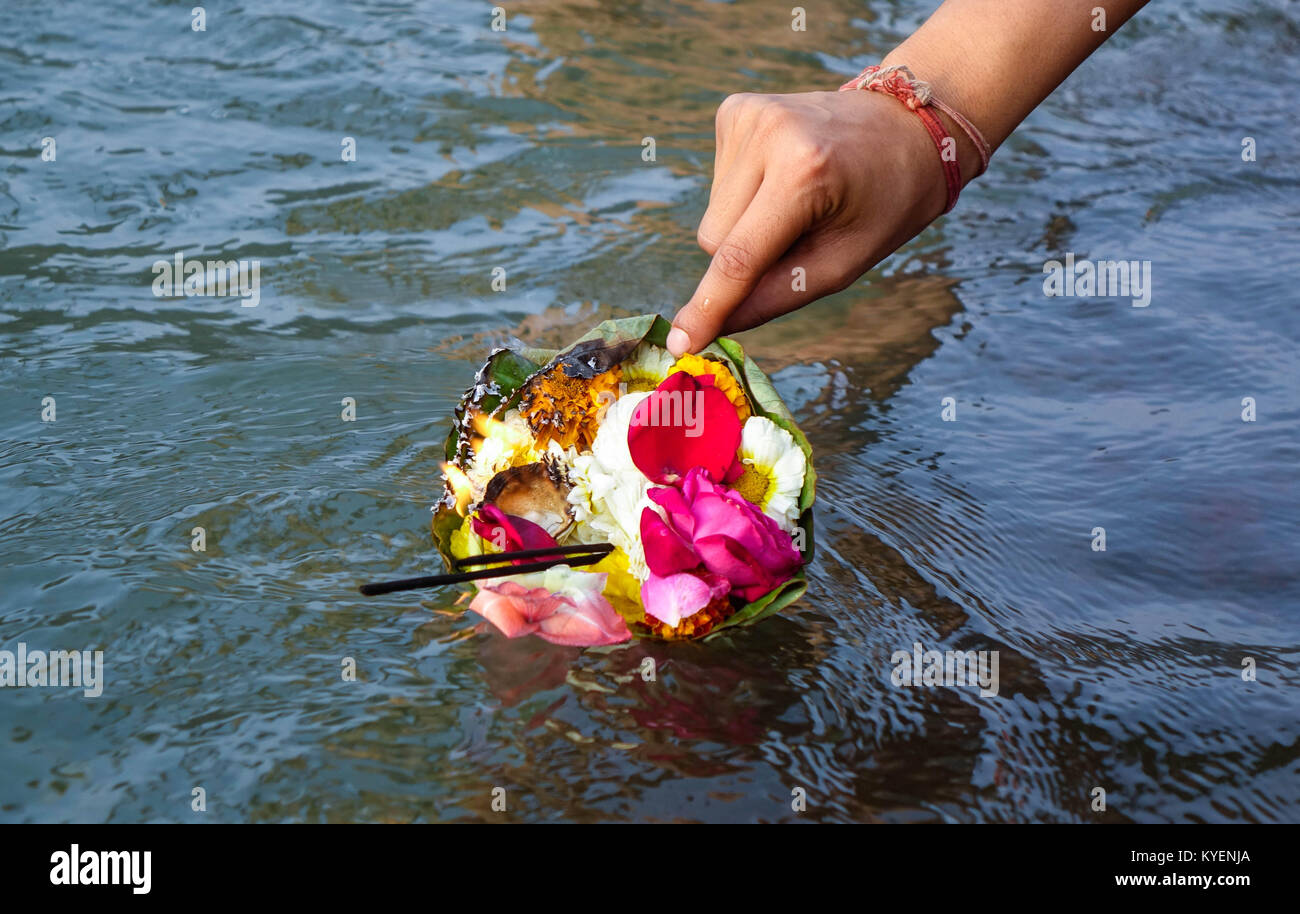 A woman's hand floating a holy package of flowers and agarbatti in