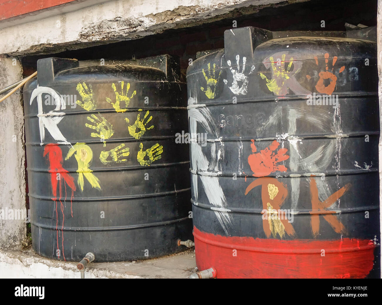 A abstract art by local kids Yellow colored hand prints on black background water tank and rough R letter written Stock Photo