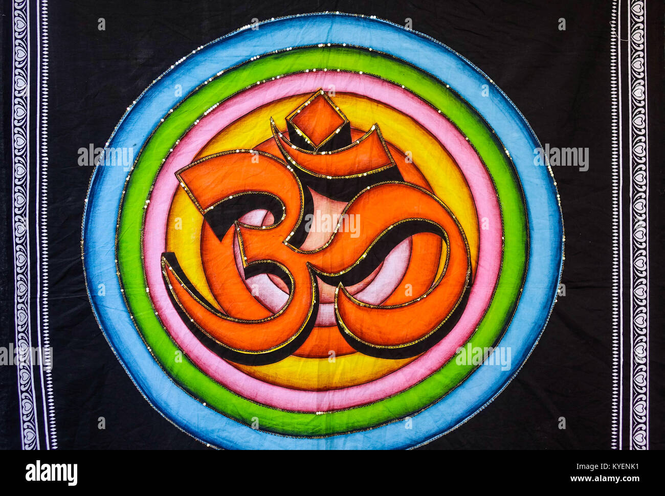 Oum or aum symbol painted on black fabric cloth in orange,  blue, green, pink colors. Stock Photo