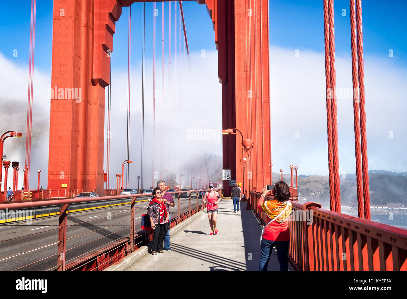 SAN FRANCISCO, CA- Oct. 11, 2015: On the Golden Gate Bridge on a sunny day with fog in the background. People in the pedestrian lanes are shown taking Stock Photo